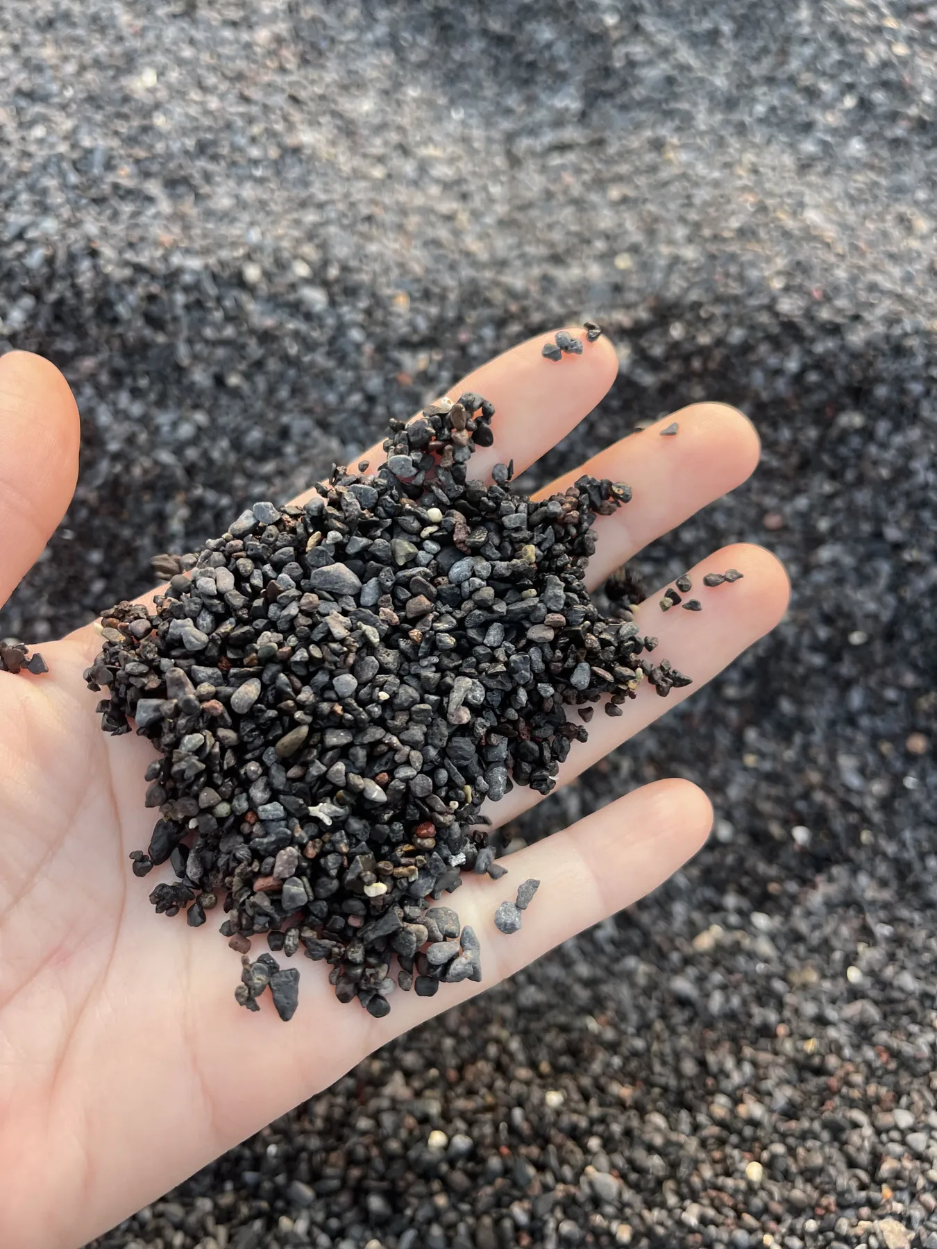 Sorra volcànica negra al palmell de la mà